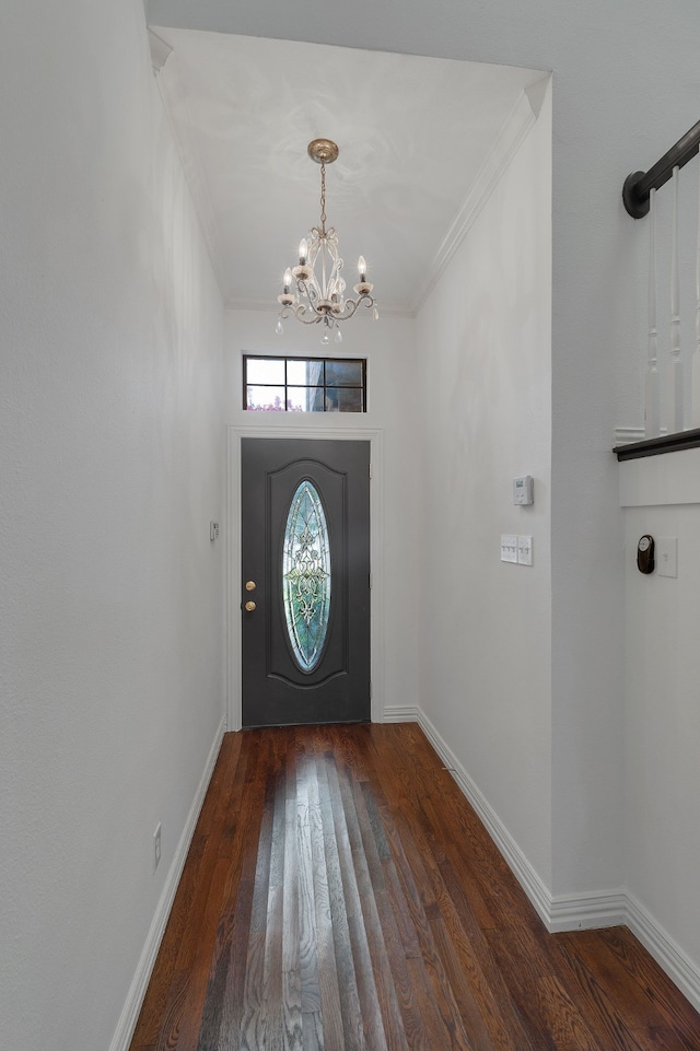 entryway with ornamental molding, an inviting chandelier, and dark wood-type flooring