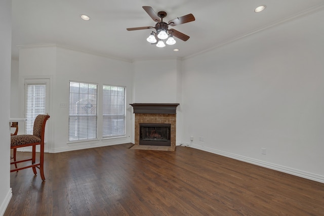 unfurnished living room with a tiled fireplace, ceiling fan, dark hardwood / wood-style floors, and crown molding