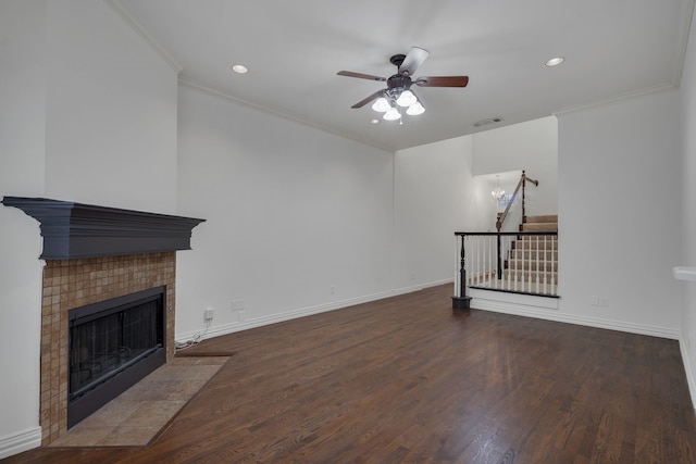 unfurnished living room with ornamental molding, a tiled fireplace, ceiling fan, and dark hardwood / wood-style flooring