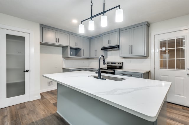 kitchen with light stone counters, a center island with sink, and stainless steel electric range