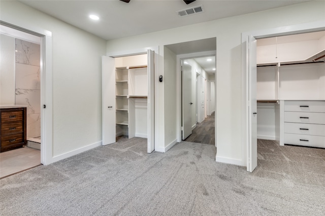 unfurnished bedroom with light carpet, connected bathroom, and a spacious closet