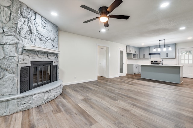 unfurnished living room featuring light hardwood / wood-style floors, ceiling fan, and a fireplace