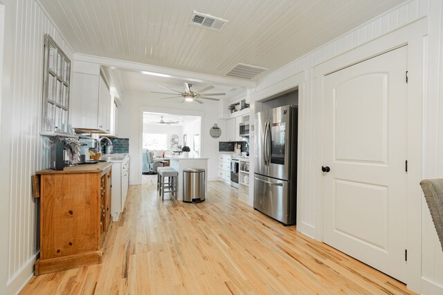 kitchen featuring light hardwood / wood-style floors, a breakfast bar area, white cabinetry, stainless steel appliances, and ceiling fan