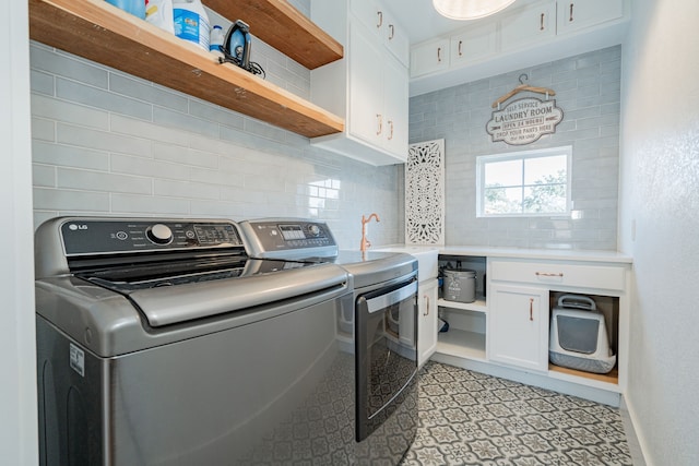 clothes washing area featuring washer and clothes dryer, sink, and cabinets