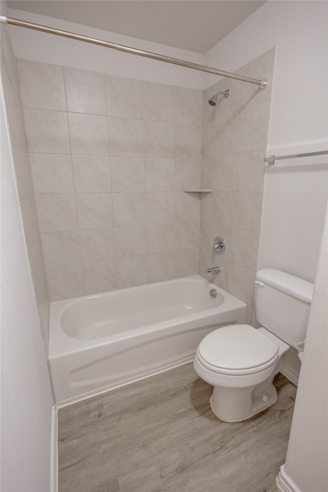 bathroom featuring tiled shower / bath, wood-type flooring, and toilet