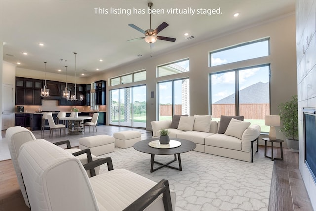 living room with ceiling fan, light hardwood / wood-style flooring, and crown molding