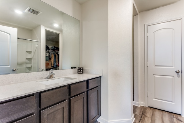 bathroom with a shower with door, vanity, and hardwood / wood-style floors