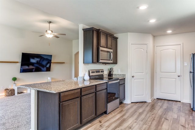 kitchen with light hardwood / wood-style floors, stainless steel appliances, dark brown cabinets, and light stone counters