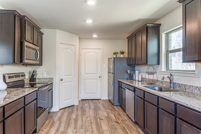 kitchen featuring light hardwood / wood-style flooring, stainless steel appliances, sink, and light stone counters