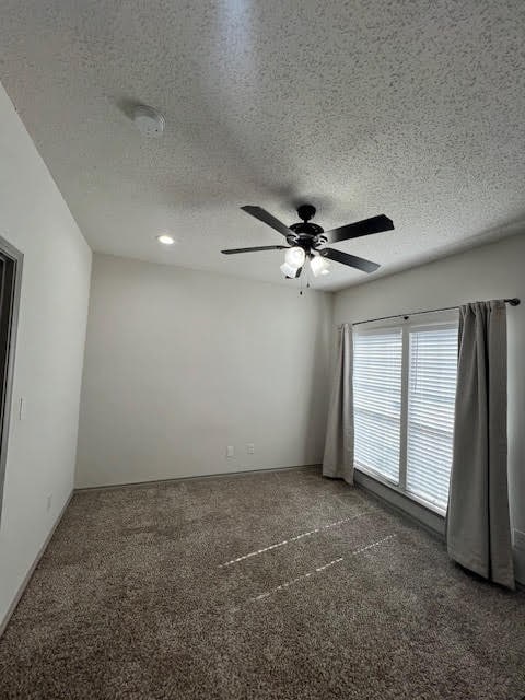 carpeted spare room with a textured ceiling and ceiling fan