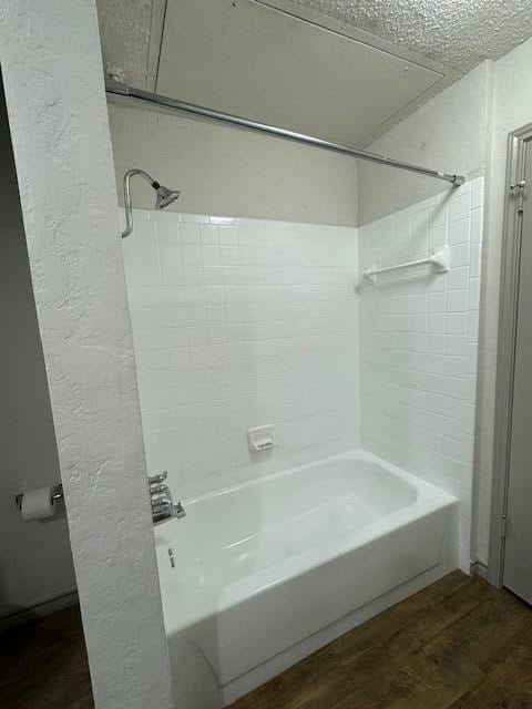 bathroom featuring a textured ceiling, bathing tub / shower combination, and hardwood / wood-style flooring