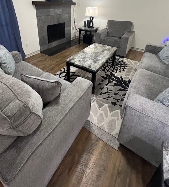 living room featuring a tile fireplace and dark hardwood / wood-style flooring