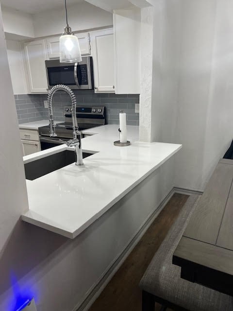 kitchen featuring pendant lighting, white cabinets, black range with electric cooktop, and kitchen peninsula