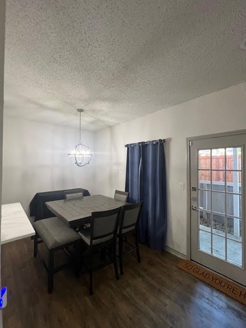 dining space featuring a notable chandelier, a textured ceiling, and dark wood-type flooring