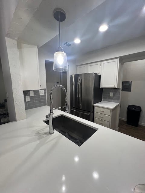 kitchen with pendant lighting, dark hardwood / wood-style floors, white cabinetry, stainless steel refrigerator, and decorative backsplash