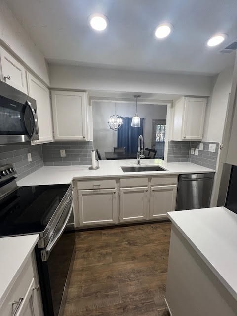 kitchen featuring pendant lighting, appliances with stainless steel finishes, sink, and white cabinets