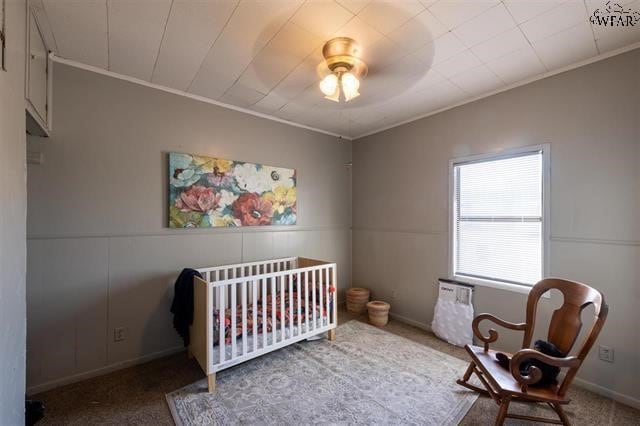 bedroom with carpet, ceiling fan, a nursery area, and crown molding