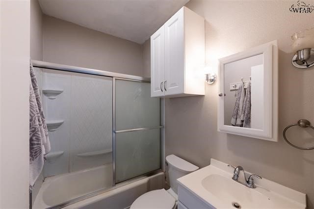 full bathroom with toilet, vanity, and bath / shower combo with glass door