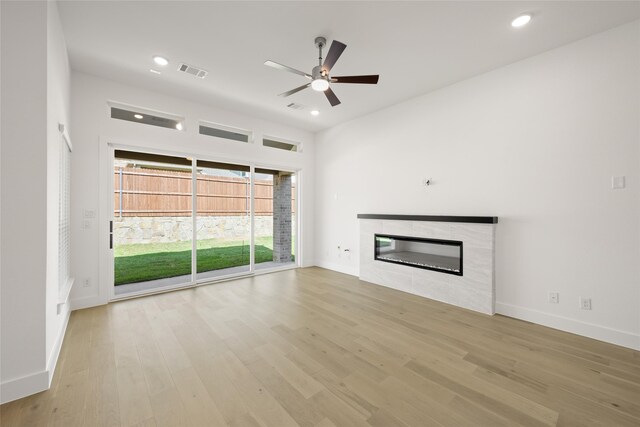 unfurnished living room with ceiling fan, a fireplace, and light hardwood / wood-style floors