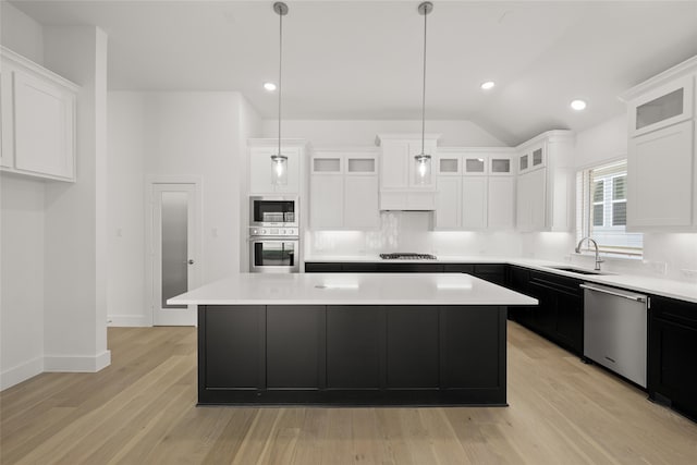 kitchen with decorative light fixtures, stainless steel appliances, a kitchen island, and white cabinetry