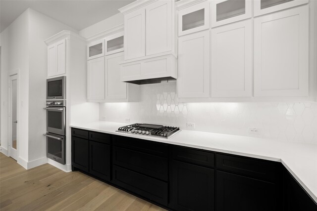 kitchen featuring white cabinets, appliances with stainless steel finishes, tasteful backsplash, and light hardwood / wood-style floors