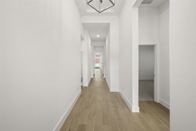 hall with light wood-type flooring and ornamental molding