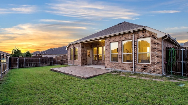 back house at dusk with a patio area and a yard