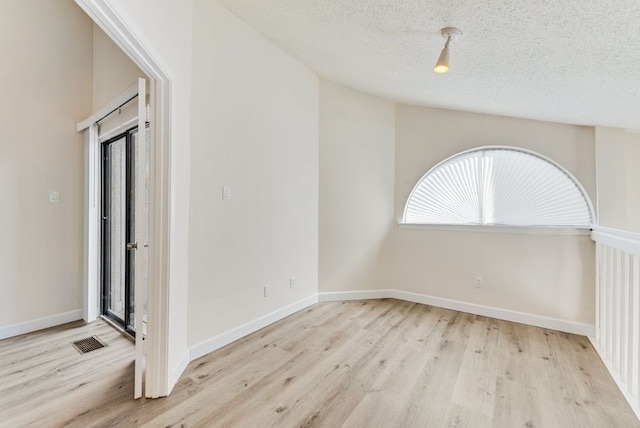 unfurnished room with a textured ceiling and light hardwood / wood-style flooring