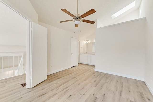 unfurnished room featuring ceiling fan, a skylight, light hardwood / wood-style floors, and high vaulted ceiling