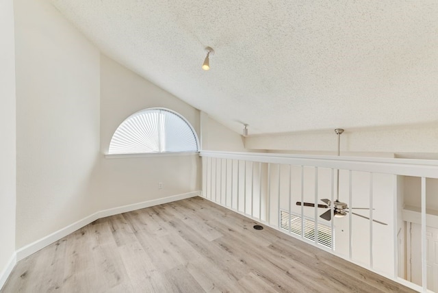 additional living space with ceiling fan, a textured ceiling, light wood-type flooring, and lofted ceiling