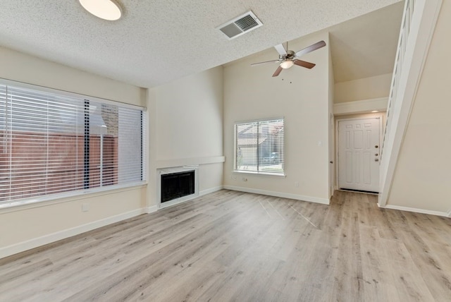 unfurnished living room with a textured ceiling, light hardwood / wood-style floors, and ceiling fan