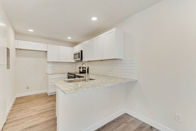 kitchen with light hardwood / wood-style flooring, stainless steel appliances, white cabinetry, and backsplash