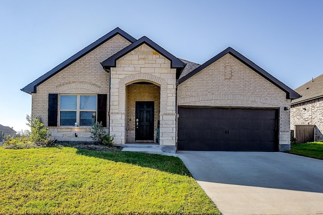 french country style house featuring a garage and a front lawn