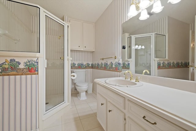 bathroom with tile patterned flooring, a notable chandelier, a shower with door, vanity, and toilet