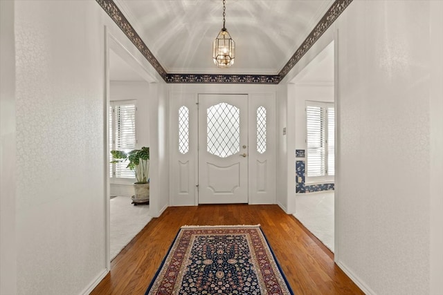 foyer with a healthy amount of sunlight, crown molding, hardwood / wood-style floors, and a notable chandelier