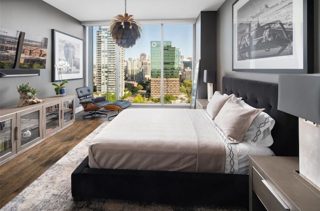 bedroom with floor to ceiling windows and dark hardwood / wood-style flooring