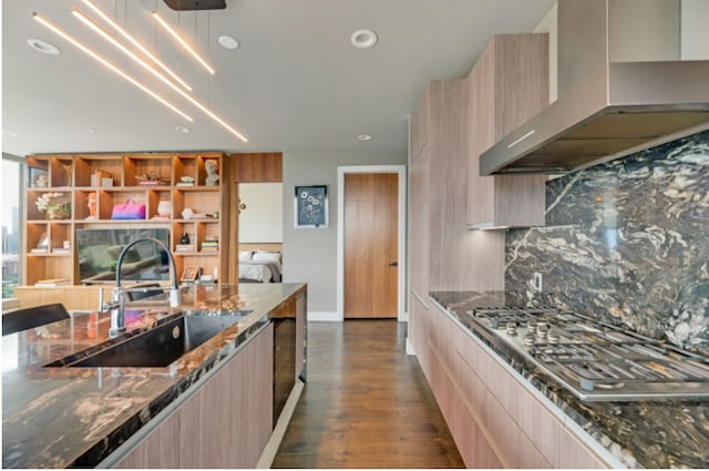 kitchen featuring wall chimney exhaust hood, dark hardwood / wood-style floors, and dark stone counters