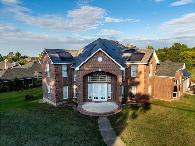 view of front of house featuring french doors, a front yard, solar panels, and a patio area