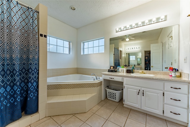 bathroom featuring vanity, a textured ceiling, tile patterned flooring, ceiling fan, and a relaxing tiled tub