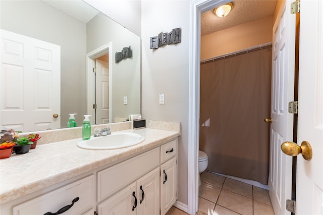 bathroom with a textured ceiling, vanity, toilet, and tile patterned floors