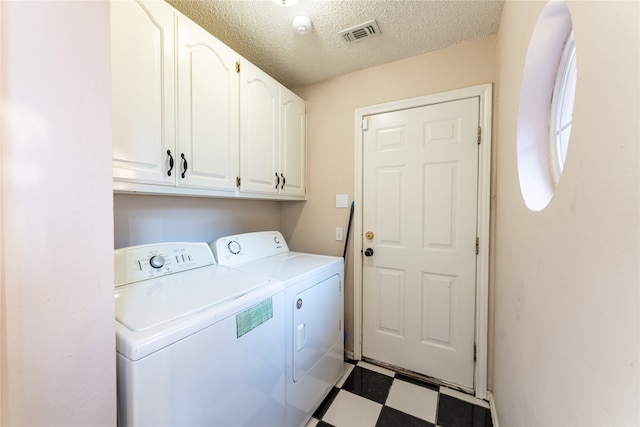 laundry room featuring cabinets, a textured ceiling, and washer and dryer