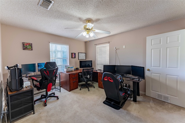 carpeted office with a textured ceiling and ceiling fan