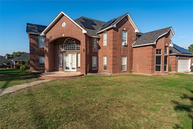 view of property featuring a front lawn, solar panels, french doors, and a garage