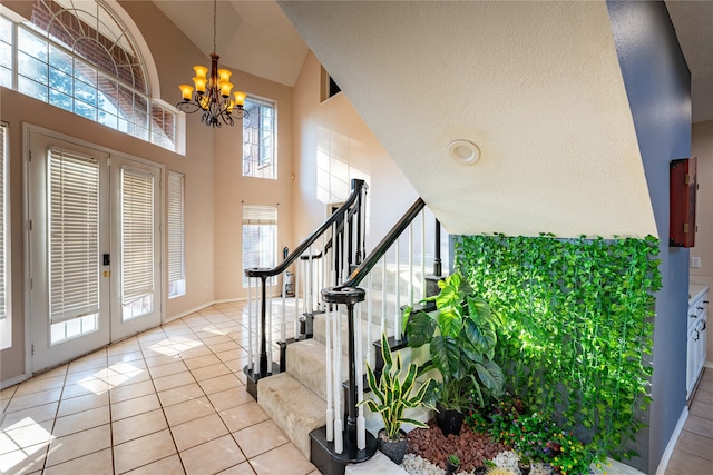 entryway with high vaulted ceiling, a chandelier, a textured ceiling, and light tile patterned floors