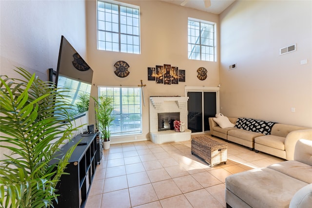 tiled living room featuring a fireplace, a high ceiling, and a wealth of natural light