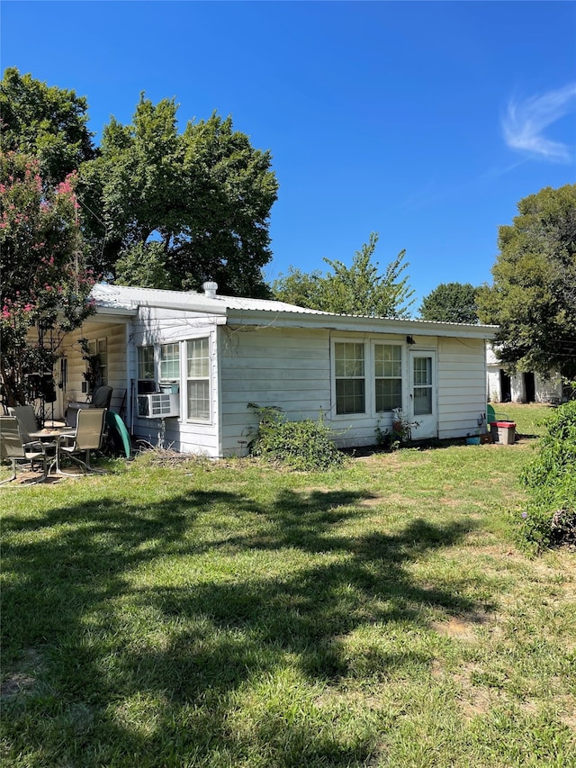 rear view of property featuring a yard and cooling unit