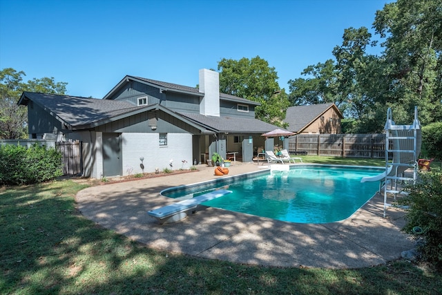 view of pool featuring a patio, a diving board, a yard, and a water slide