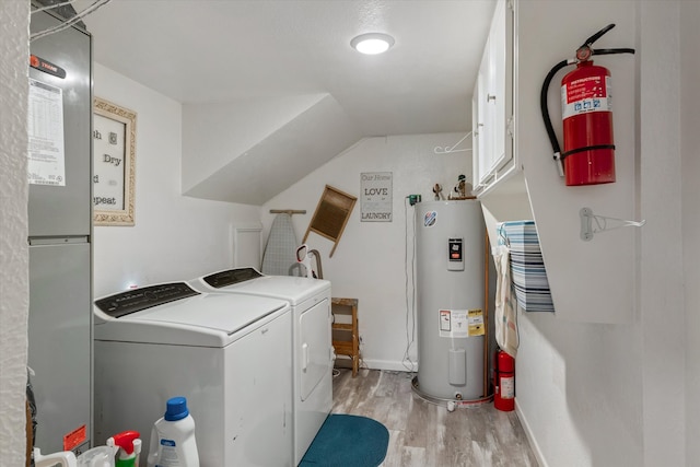 laundry area with washer and clothes dryer, cabinets, water heater, and light hardwood / wood-style flooring