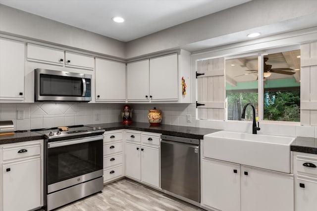 kitchen with light wood-type flooring, tasteful backsplash, sink, white cabinets, and stainless steel appliances