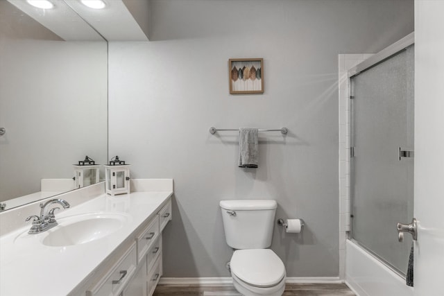 full bathroom featuring shower / bath combination with glass door, hardwood / wood-style floors, vanity, and toilet